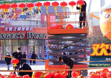 北京欢乐谷工作人员用升降平台车悬挂新年灯笼